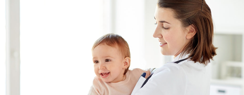 doctor or pediatrician holding baby at clinic